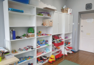 Gabinet 102 do Play Therapy. Regały z pomocami terapeutycznymi dla dzieci - zabawki: samochody, lalki, pacynki, instrumenty muzyczne, zestaw lekarza, maski.