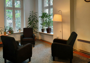 Gabinet 107 do terapii rodzin. Duże pomieszczenie, trzy fotele w kolorze ciemnym, lampa,dwa okna.