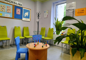 Poczekalnia poradni. Pięć krzeseł dla dorosłych w kolorze zielonym, dwa krzesła dla dzieci w kolorze niebieskim.